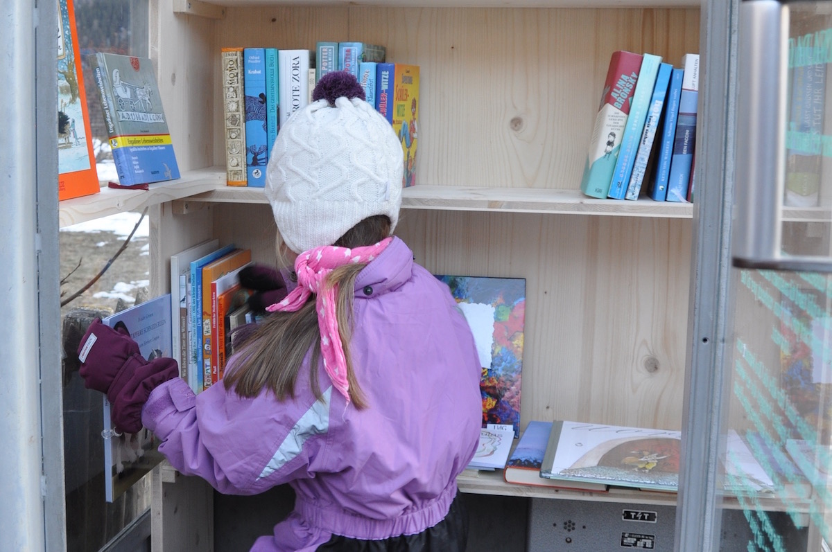 Little kid getting a book from the Cabina